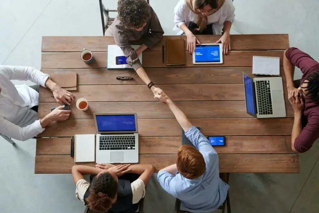 Overhead view of colleagues in a work meeting using laptops and tablets, emphasizing teamwork and technology.